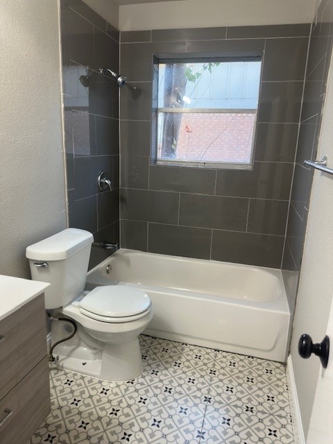 full bathroom with tiled shower / bath, vanity, toilet, and tile floors