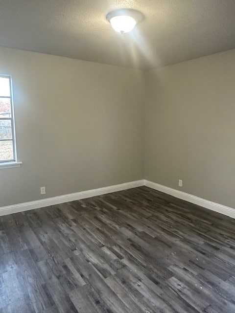 unfurnished room with dark hardwood / wood-style flooring and a textured ceiling