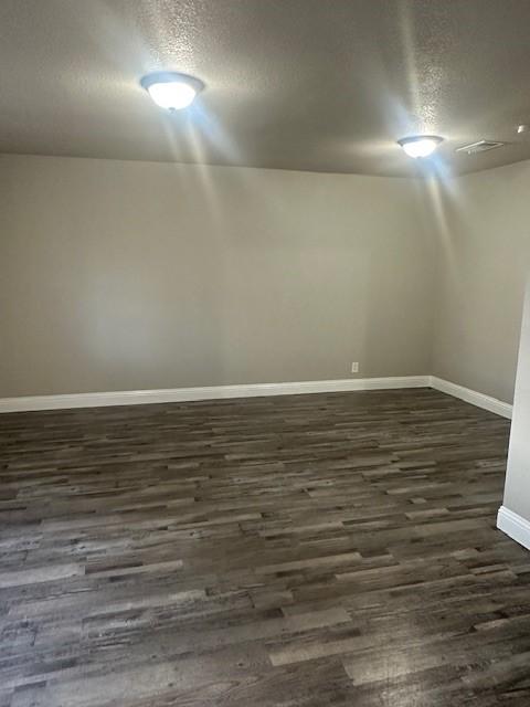 empty room with dark hardwood / wood-style flooring and a textured ceiling