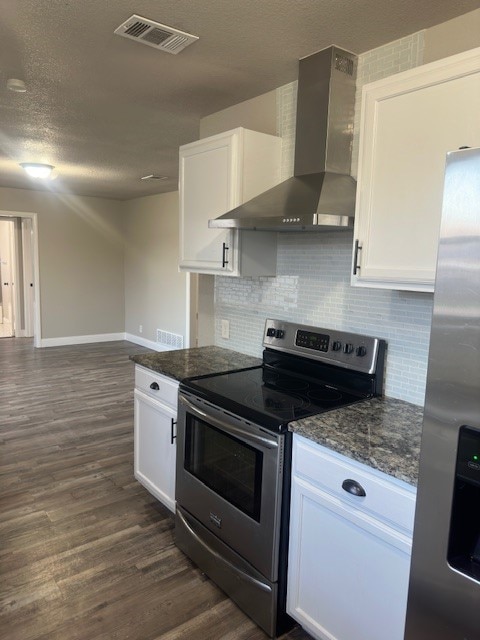 kitchen with dark hardwood / wood-style flooring, stainless steel appliances, white cabinets, wall chimney exhaust hood, and backsplash