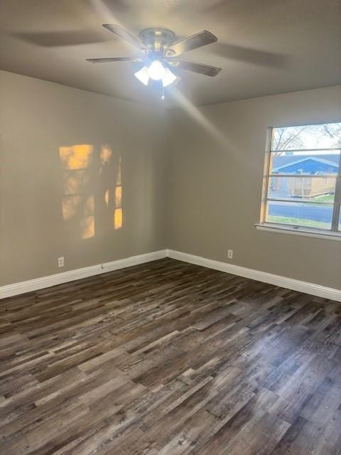 empty room featuring baseboards, dark wood finished floors, and a ceiling fan