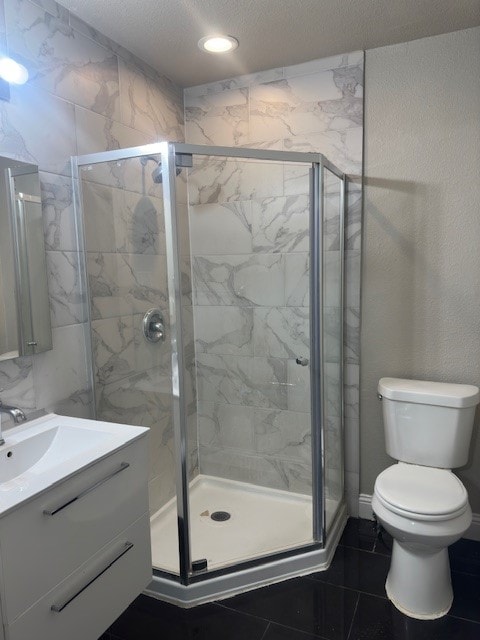 bathroom with tile floors, a shower with door, large vanity, and toilet