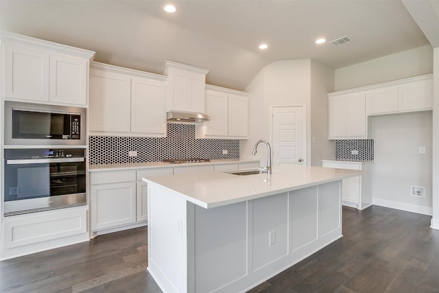 kitchen with appliances with stainless steel finishes, a center island with sink, sink, and dark hardwood / wood-style floors