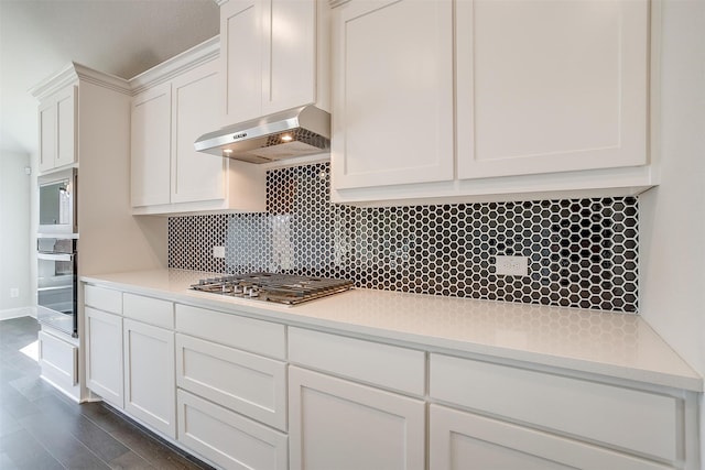 kitchen featuring tasteful backsplash, dark wood-type flooring, white cabinetry, appliances with stainless steel finishes, and range hood