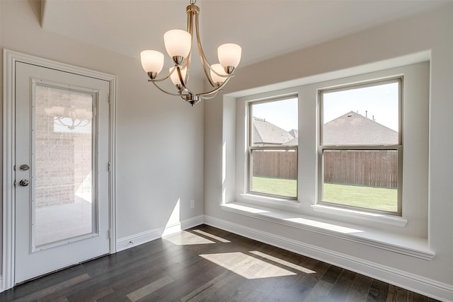 unfurnished dining area featuring a healthy amount of sunlight, dark hardwood / wood-style flooring, and a notable chandelier