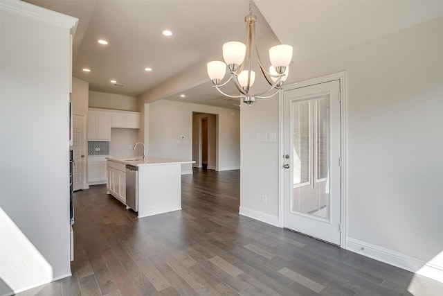 kitchen featuring pendant lighting, dark wood-type flooring, sink, a notable chandelier, and a center island with sink