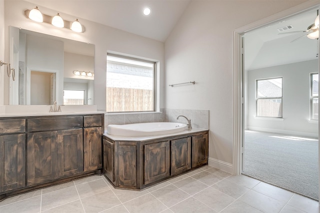 bathroom featuring vanity, vaulted ceiling, plenty of natural light, and a washtub