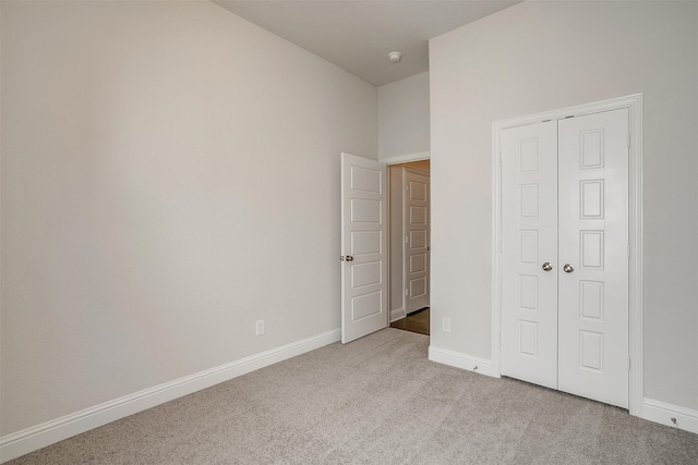 unfurnished bedroom with light colored carpet and a closet