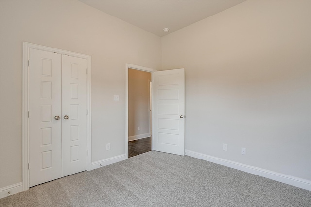 unfurnished bedroom with dark colored carpet and a closet