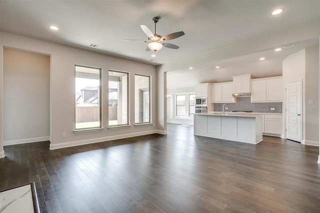 unfurnished living room featuring dark hardwood / wood-style flooring, ceiling fan, and sink