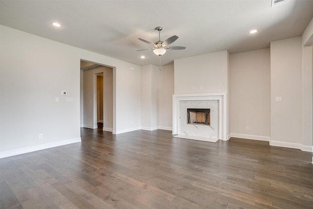 unfurnished living room featuring ceiling fan, a fireplace, and dark hardwood / wood-style floors