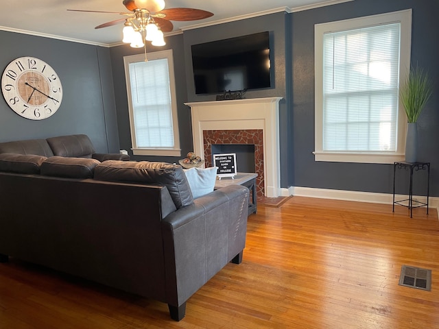 living room with ceiling fan, plenty of natural light, hardwood / wood-style flooring, and ornamental molding