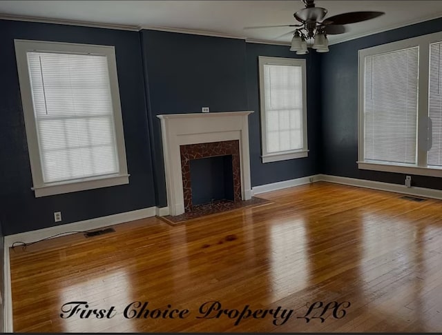 unfurnished living room featuring crown molding, ceiling fan, a fireplace, and a healthy amount of sunlight