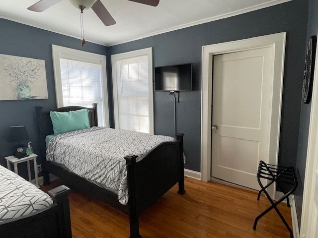 bedroom featuring ceiling fan, crown molding, and dark wood-type flooring