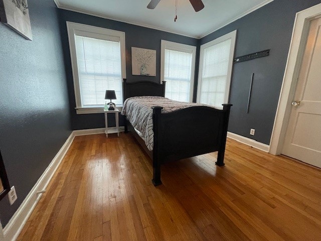 bedroom with wood-type flooring, ceiling fan, and ornamental molding