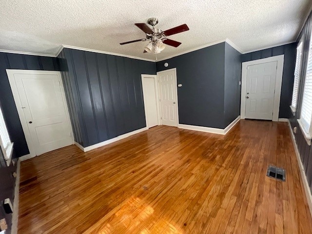 interior space with ceiling fan, crown molding, wood-type flooring, and a textured ceiling