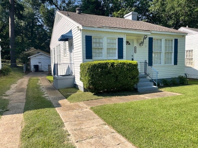 bungalow with a front yard, an outbuilding, and a garage