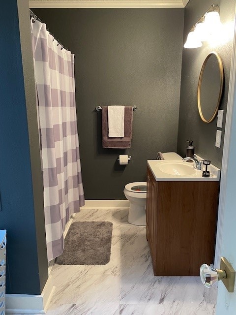 bathroom with toilet, vanity, and ornamental molding