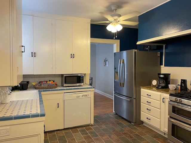 kitchen with ceiling fan, sink, backsplash, white cabinets, and appliances with stainless steel finishes