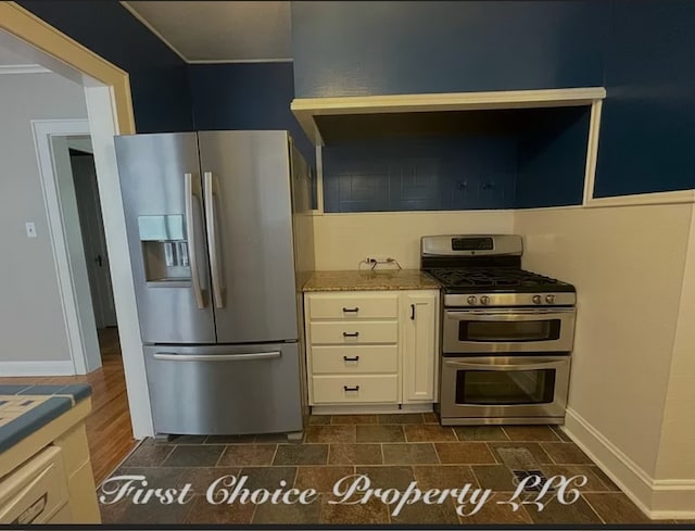 kitchen featuring light stone counters, white cabinets, and stainless steel appliances