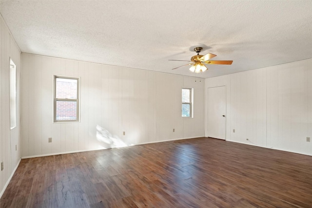 spare room with wood walls, dark hardwood / wood-style floors, ceiling fan, and a textured ceiling