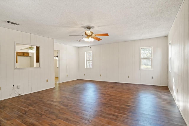 spare room with a healthy amount of sunlight, ceiling fan, dark wood-type flooring, and a textured ceiling