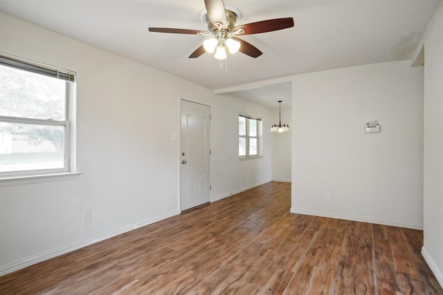 unfurnished room with hardwood / wood-style floors and ceiling fan with notable chandelier