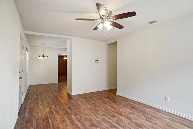 empty room with ceiling fan with notable chandelier and hardwood / wood-style flooring