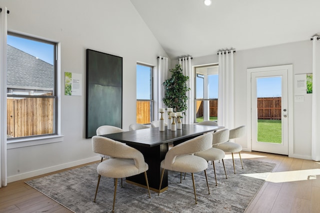 dining area featuring high vaulted ceiling and light hardwood / wood-style floors