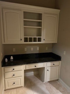 interior space featuring white cabinets, built in desk, and light tile patterned floors