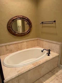 bathroom featuring tile patterned flooring and tiled bath