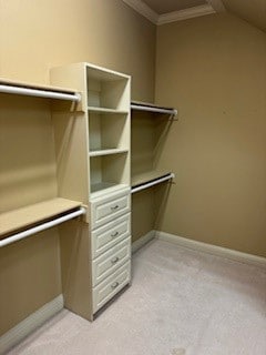 walk in closet with light colored carpet and lofted ceiling