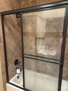 bathroom with bath / shower combo with glass door