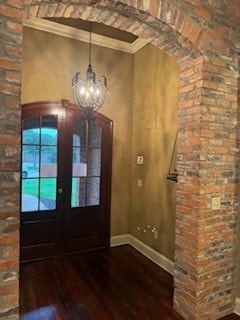 foyer entrance with hardwood / wood-style floors, ornamental molding, french doors, and a notable chandelier