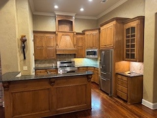 kitchen with kitchen peninsula, dark hardwood / wood-style flooring, stainless steel appliances, and ornamental molding