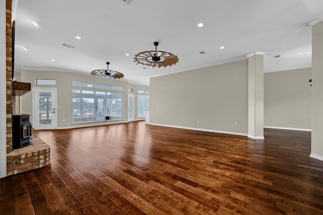 unfurnished living room with dark hardwood / wood-style flooring, crown molding, ceiling fan, and a wood stove