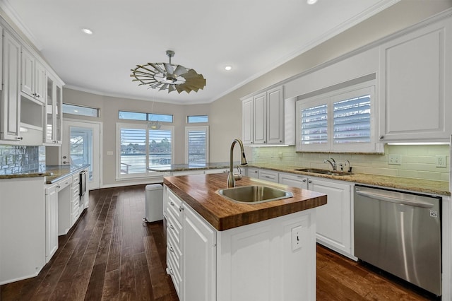 kitchen featuring stainless steel dishwasher, sink, an island with sink, and white cabinets