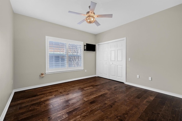 unfurnished bedroom with dark wood-type flooring, a closet, and ceiling fan