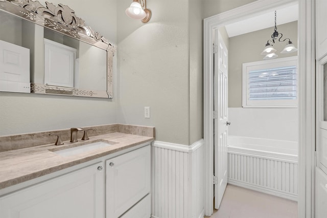 bathroom featuring an inviting chandelier, a tub to relax in, and vanity