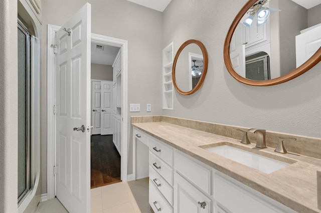 bathroom with a shower with door, vanity, and tile patterned floors