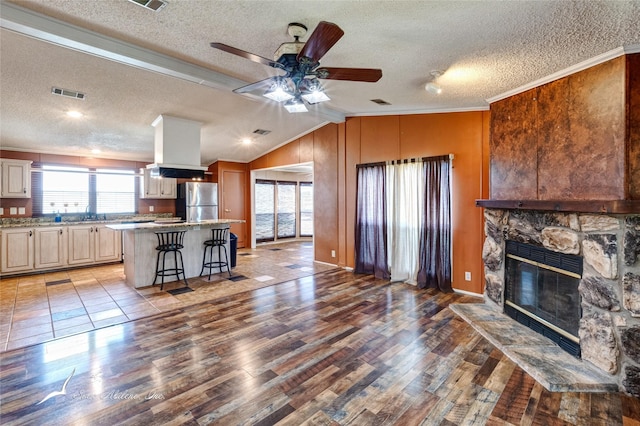 living room with a stone fireplace, vaulted ceiling, light hardwood / wood-style floors, and ceiling fan