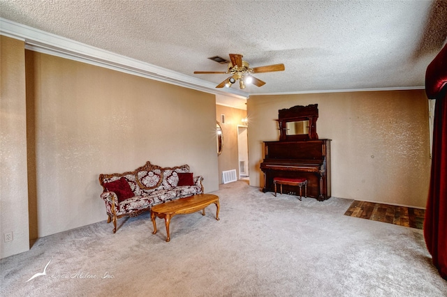 sitting room with ornamental molding, carpet flooring, a textured ceiling, and ceiling fan