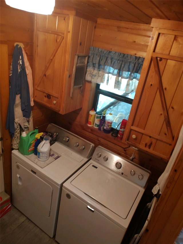 laundry room featuring wooden walls and washing machine and clothes dryer