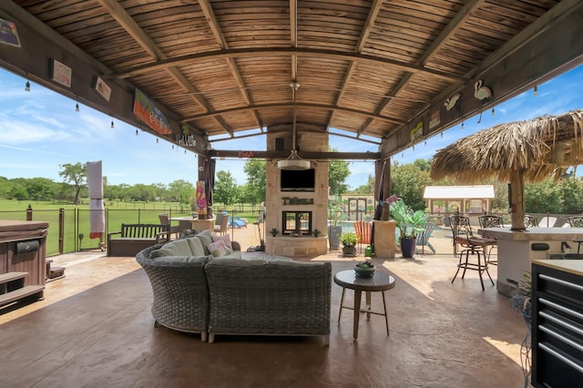 view of patio / terrace featuring an outdoor living space with a fireplace, a bar, and a gazebo