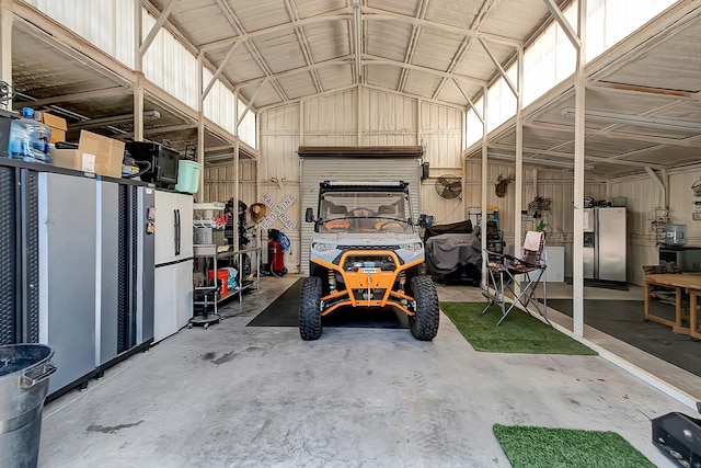 garage featuring stainless steel refrigerator with ice dispenser and white fridge