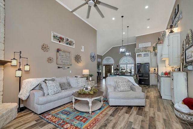 living room with ceiling fan, crown molding, and a towering ceiling