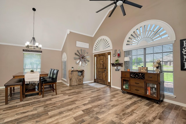 entryway featuring high vaulted ceiling, wood-type flooring, ceiling fan with notable chandelier, and ornamental molding