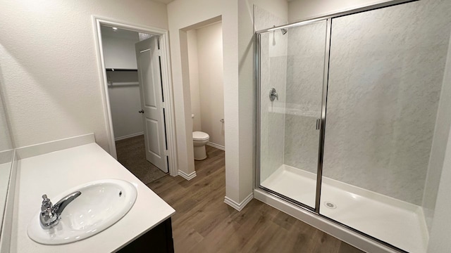 bathroom featuring hardwood / wood-style flooring, vanity, toilet, and a shower with shower door