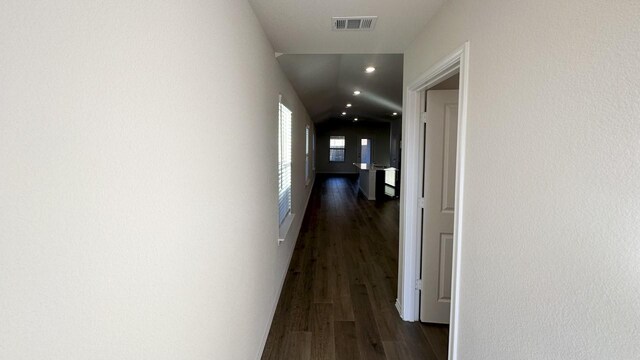 corridor with dark hardwood / wood-style flooring and vaulted ceiling