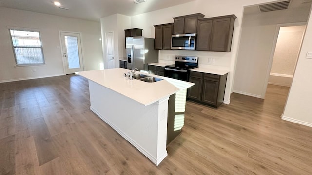 kitchen featuring dark brown cabinetry, sink, light hardwood / wood-style flooring, and appliances with stainless steel finishes